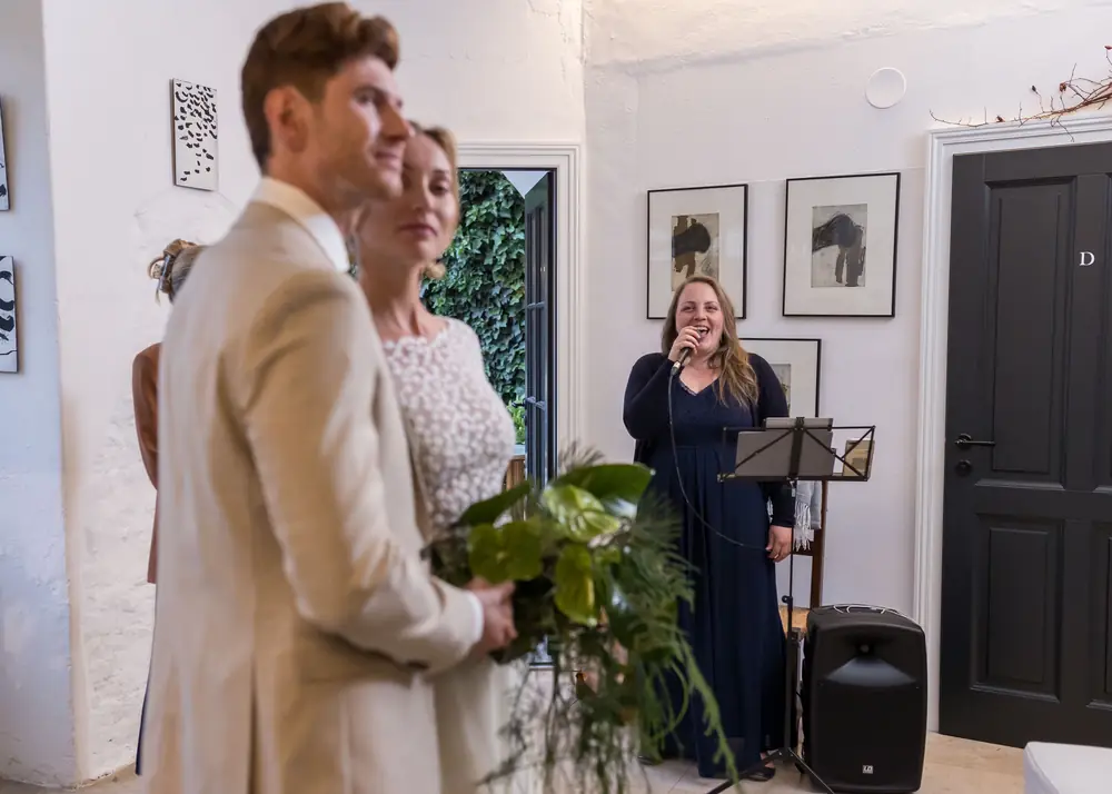 Brautpaar bei der Trauung, im Hintergrund singt Melanie Fedl
